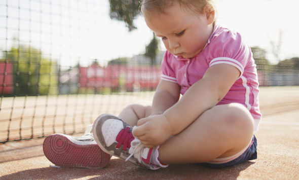 little girl learning to tie shoelaces outside